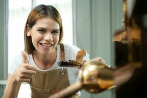 Portrait of a young woman working with a coffee roaster machine photo