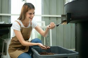 Portrait of a young woman working with a coffee roaster machine photo