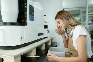 Young woman in apron using digital tablet for checking quality of of coffee beans with digital roaster photo