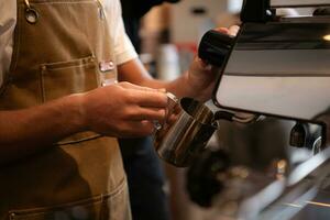 Cropped image of barista steam milk for making latte coffee at counter cafe photo