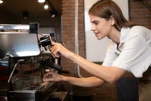 Young female barista preparing coffee in cafe. Female barista using coffee machine. photo