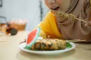 Muslim girl eating mushroom sushi at the restaurant. Selective focus on sushi photo