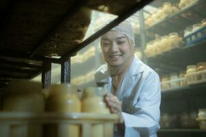 Young asian muslim female scientist doing research at a mushroom factory, examining mushroom leavening agent in a sterile and temperature-controlled room. photo