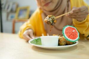 Muslim girl eating mushroom sushi at the restaurant. Selective focus on sushi photo