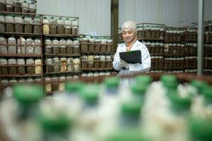 Young asian muslim female scientist doing research at a mushroom factory, examining mushroom leavening agent in a sterile and temperature-controlled room. photo