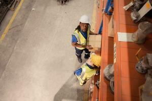 alto ángulo ver de almacén trabajadores en sombreros duros levantamiento cajas a almacén foto