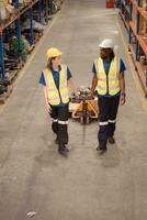 Top view of two warehouse workers pushing a pallet truck in a shipping and distribution warehouse. photo