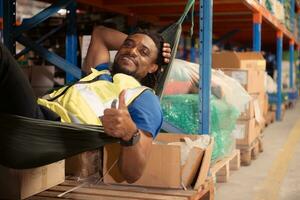 Portrait of happy mature African American man relaxing in hammock in warehouse photo