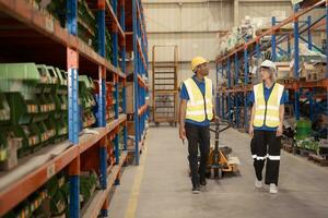 Two warehouse workers pushing a pallet truck in a shipping and distribution warehouse. photo