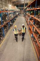 Top view of two warehouse workers pushing a pallet truck in a shipping and distribution warehouse. photo