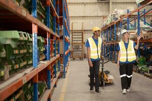 Two warehouse workers pushing a pallet truck in a shipping and distribution warehouse. photo