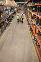 Top view of two warehouse workers pushing a pallet truck in a shipping and distribution warehouse. photo