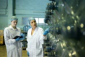 Both of female quality control workers in a drinking water factory Inspecting the quality of water tanks before importing the drinking water belt into the tank photo