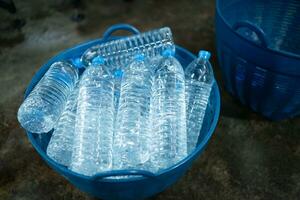 Plastic bottles of drinking water in a blue plastic basket on the floor photo