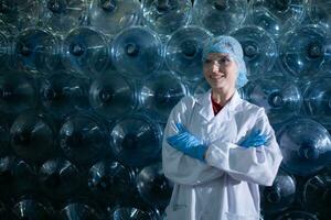 Portrait of Female scientist with arms crossed in drinking water factory, She was standing in front of a plastic bottle. photo