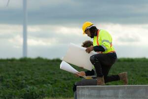 Engineers and technicians work together on the tower base of a large wind turbine with a wind turbine field in the background, The concept of natural energy from wind. photo