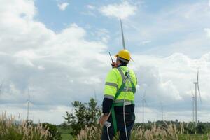 Engineers are using a smartphone to check the wind turbine in the field, The concept of natural energy from wind. photo