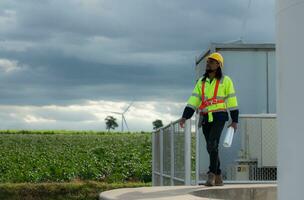 Engineer worker walking in front of wind turbines on a cloudy day, The concept of natural energy from wind. photo