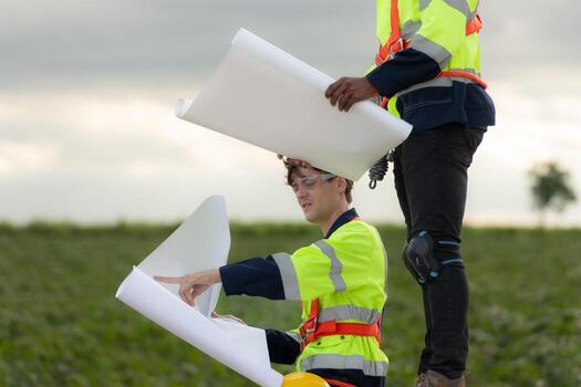 Engineers and technicians work together on the tower base of a large wind turbine with a wind turbine field in the background, The concept of natural energy from wind. photo