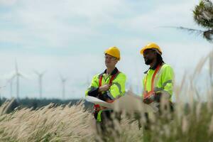 Engineer and technician discussing a solution problem of wind turbine before go in and check wind turbine, The concept of natural energy from wind. photo