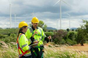 Engineer and worker discussing the project on the background of wind turbines photo