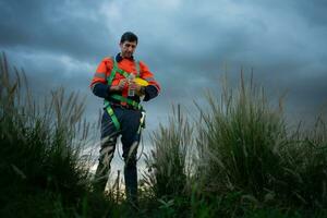 retrato de un joven hombre trabajando en viento turbina campo, vistiendo un la seguridad chaleco, el concepto de relajarse hora después trabajo foto