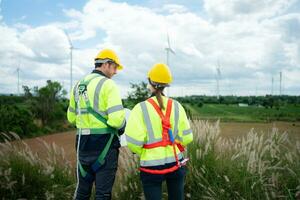 Engineer and worker discussing the project on the background of wind turbines photo