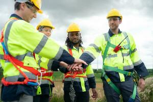 Group of engineers and technicians are discussing and looking at blueprints with wind turbines in the background photo