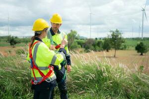 Engineer and worker discussing the project on the background of wind turbines photo