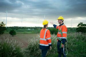 Two engineers shaking hands on the background of wind turbines in the field photo