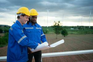 Back view of engineer and technician looking at wind turbines in the field before go in and check wind turbine, The concept of natural energy from wind. photo