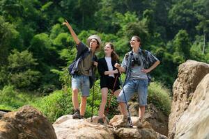 Group of tourists with backpacks walking on the trail in the river and mountains photo