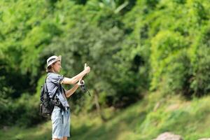 Young man with backpack hiking in the forest. Active lifestyle concept. photo