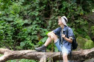 Young man traveler sitting on a fallen tree and looking at the compass in hand. photo