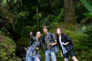 grupo de joven personas excursionismo en el bosque. viaje y aventuras concepto. foto