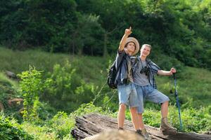 Two man hiking in the forest with backpacks and trekking poles photo