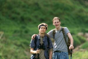 dos hombre excursionismo en el bosque con mochilas y trekking polos foto