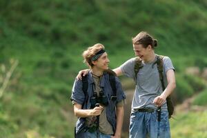 Two man hiking in the forest with backpacks and trekking poles photo