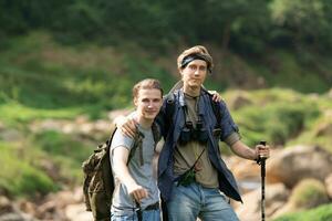 dos hombre excursionismo en el bosque con mochilas y trekking polos foto