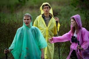 Group of friends in raincoats with backpacks on a hike in the forest, Prepare to hiking after the rain has stopped. photo