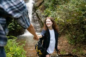 Young couple of hikers sitting on a rock and looking at each other photo