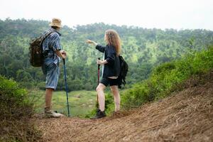 joven Pareja excursionismo en el bosque con mochilas y trekking polos foto