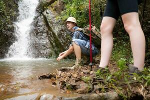 Young couple hiker with a backpack standing in front of a waterfall photo