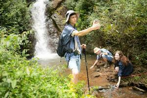 hombre y mujer caminantes tomando imágenes de sí mismos a el cascada en bosque foto