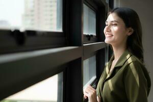 Portrait of a beautiful young woman standing near the window and smiling photo