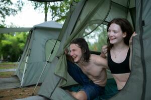 Young couple camping in tent in forest smiling happy and relaxed looking at camera photo