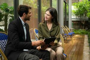 Both of businessperson using digital tablet at outdoor cafe. Business people meeting in coffee shop. photo