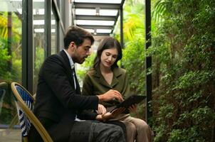 Both of businessperson using digital tablet at outdoor cafe. Business people meeting in coffee shop. photo