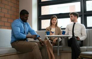 Young business people talking and drinking coffee in the office. Businessman and businesswoman having a coffee break. photo