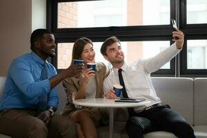 Group of business people discussing business plan at meeting in modern office. Businessman and businesswoman using mobile phone to take a selfie. photo